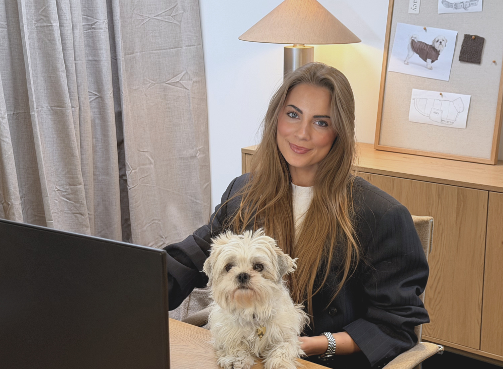 Woman working at a desk with a small white dog on her lap