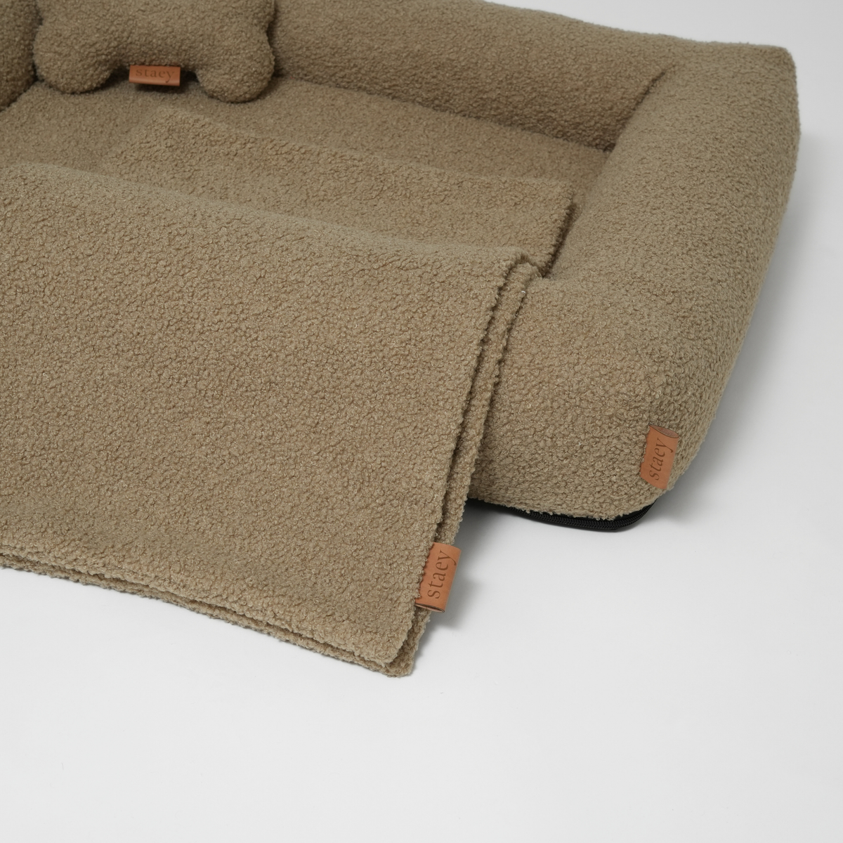 Le lit pour chien en bouclé frisé couleur mousse, avec un coussin en forme d'os et un tapis assorti