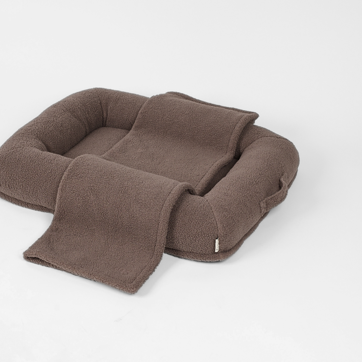 The taupe teddy dog bed with a matching blanket over the edge