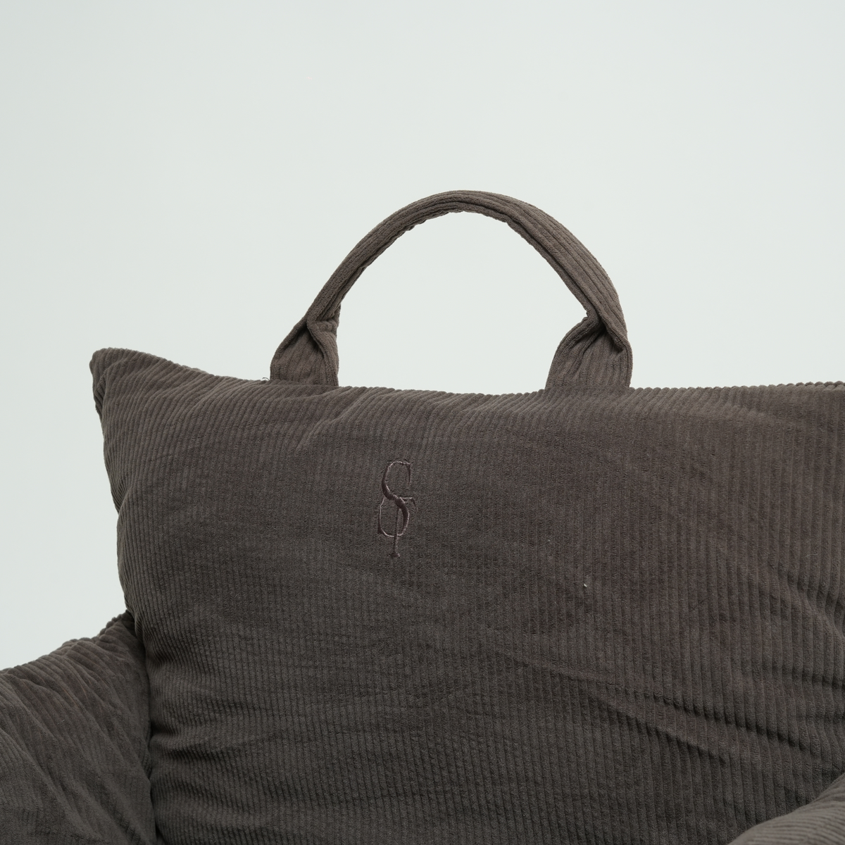 Close-up of the carry handle and embossed Staey monogram on a corduroy car seat