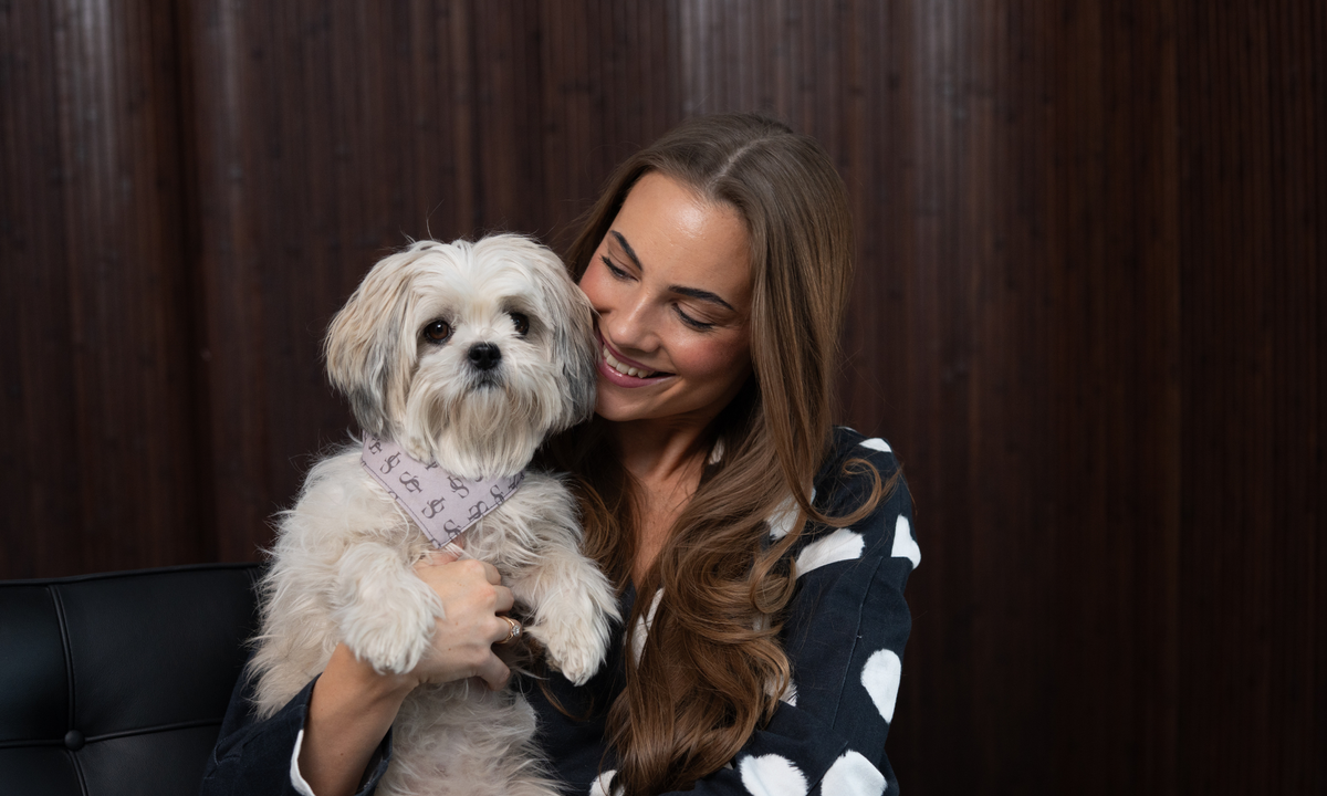 Woman holding a shih tzu wearing a Staey bandana