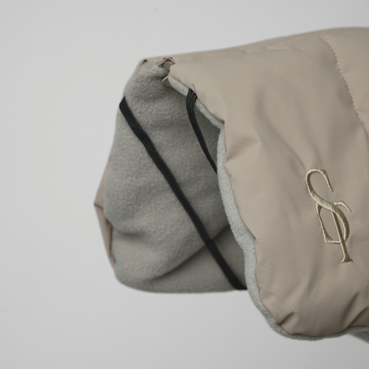 Gros plan sur le monogramme « Staey » en relief et la doublure en polaire d'un plaid pour chien de couleur taupe