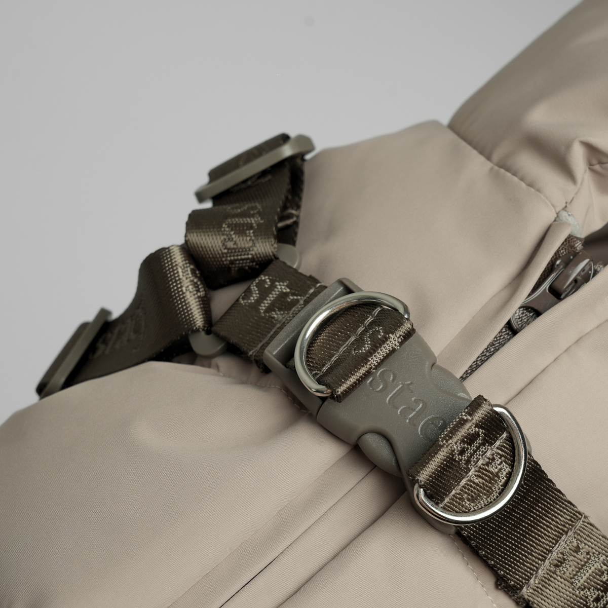 Gros plan sur la boucle du harnais et les sangles du manteau matelassé Taupe