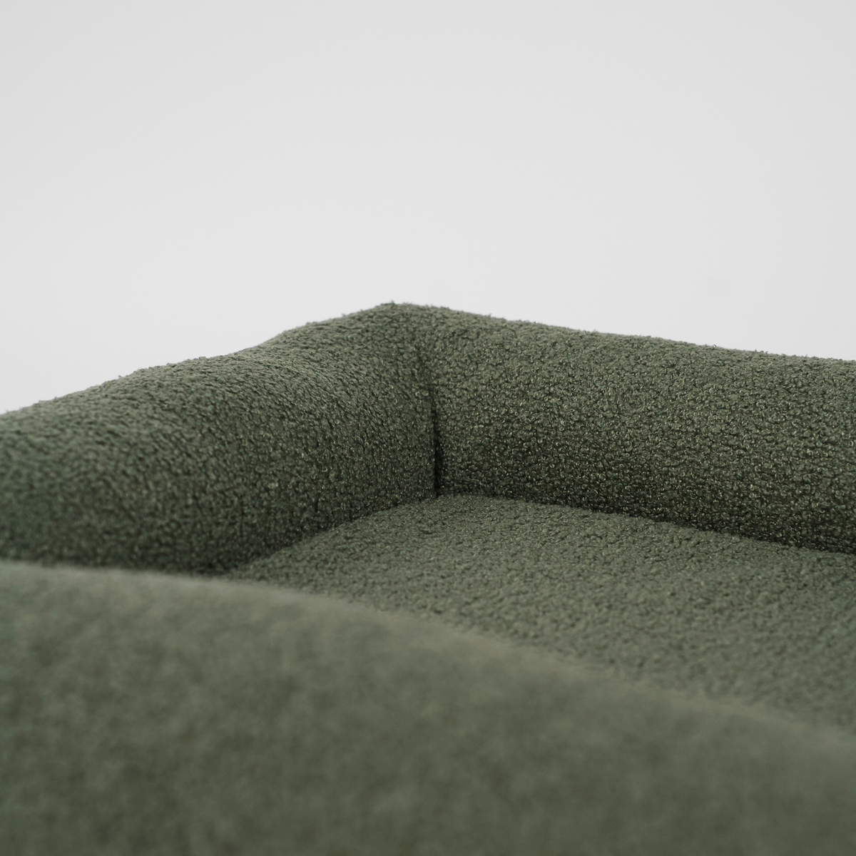 Close-up van het kussen en het kussentje van een moss green bouclé hondenmand