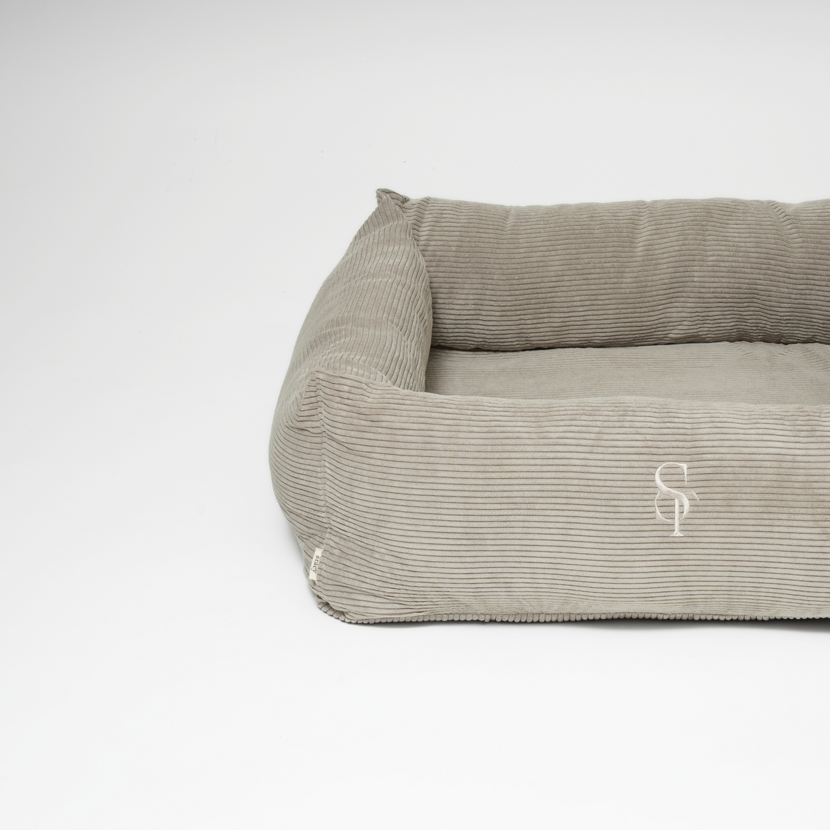 Le lit pour chien en velours côtelé taupe, orné du monogramme Staey en relief