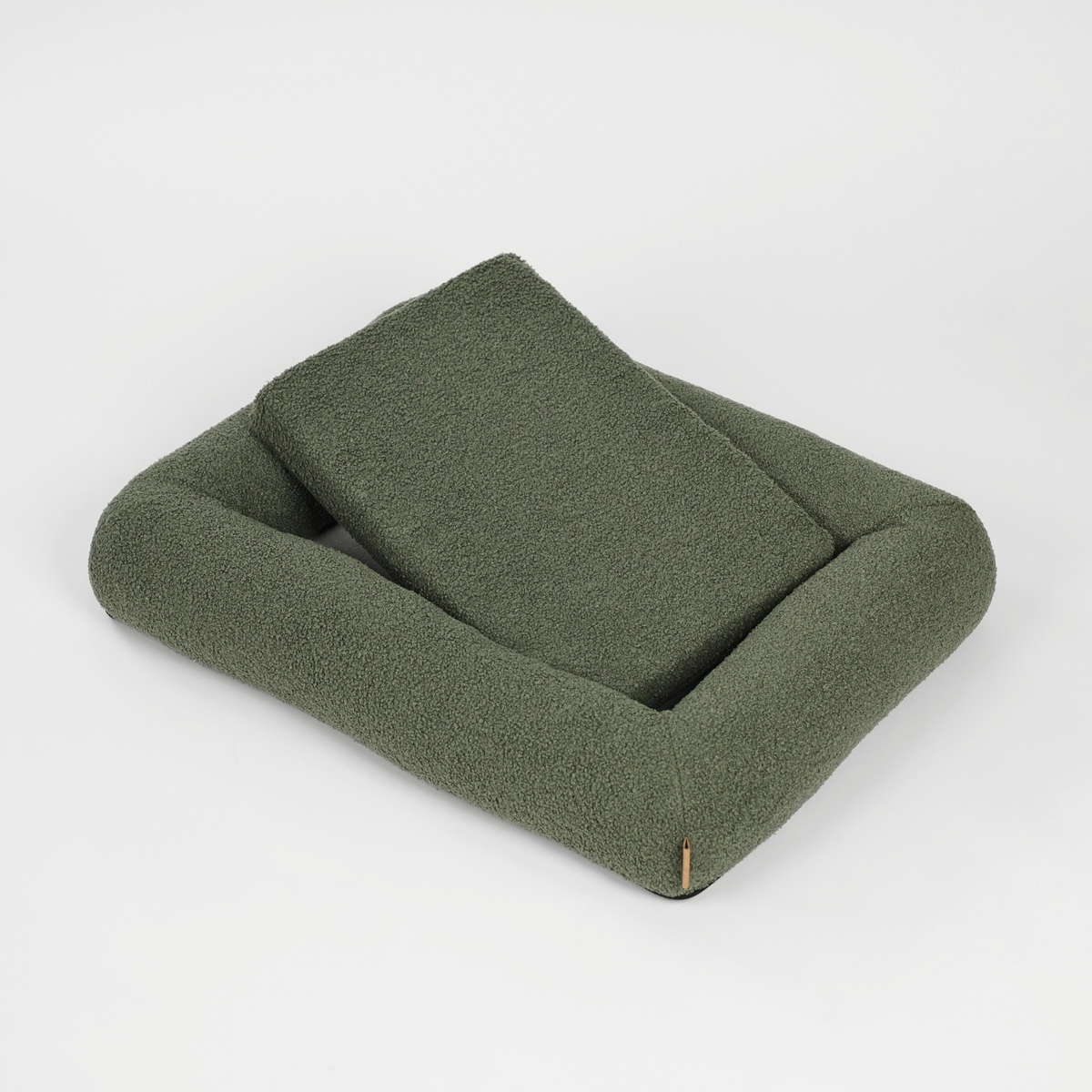 De moss green bouclé hondenmand met het kussen erin gelegd