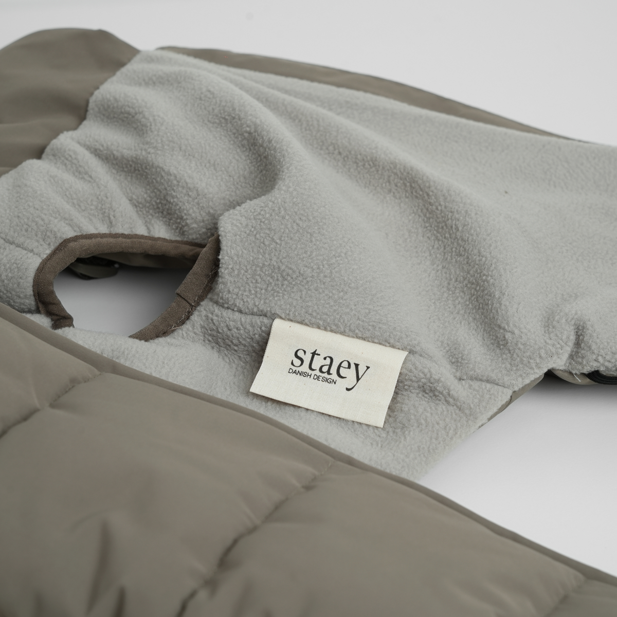 Gros plan sur l'étiquette Staey et la doublure en polaire du manteau matelassé Taupe