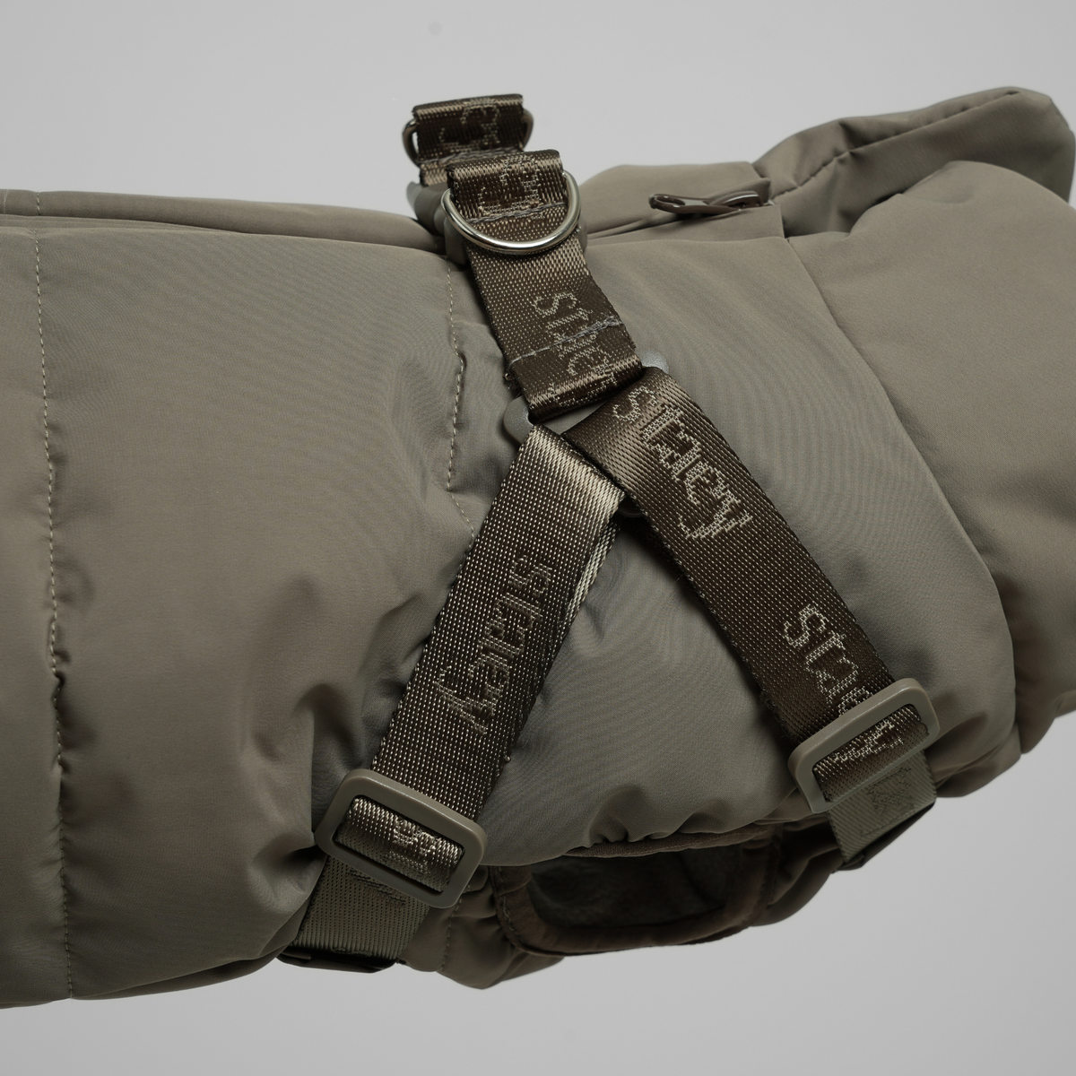Gros plan sur les sangles du harnais du manteau matelassé moss green