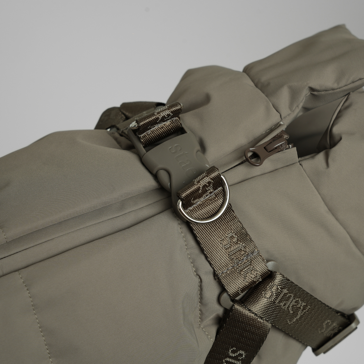 Gros plan sur l'anneau en D et la sangle Staey du manteau matelassé couleur taupe