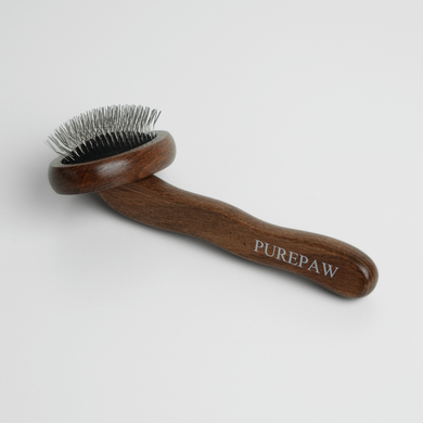 Dog grooming brush with wooden handle and metal bristles on a white background, branded 'PUREPAW'.
