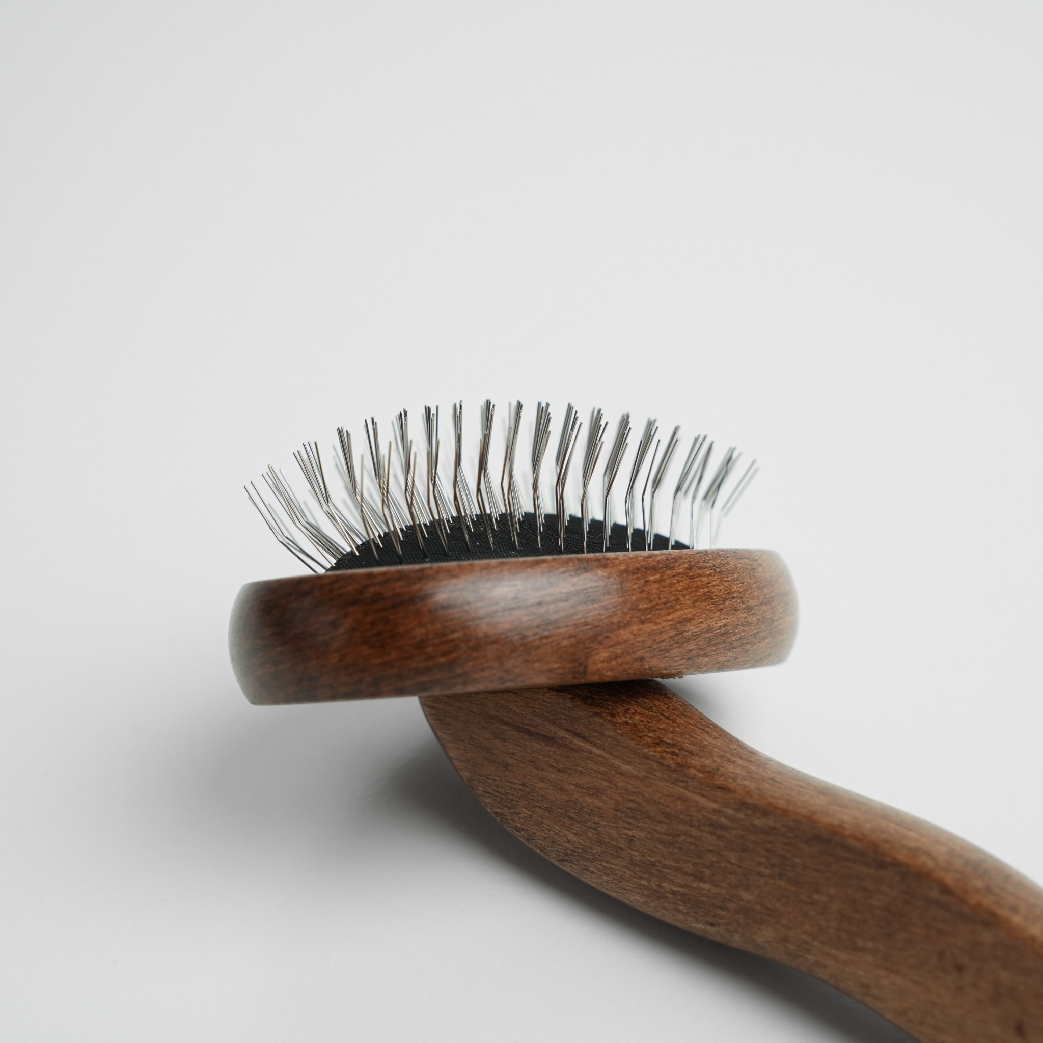 Brosse pour chien en bois avec des poils métalliques sur fond gris clair