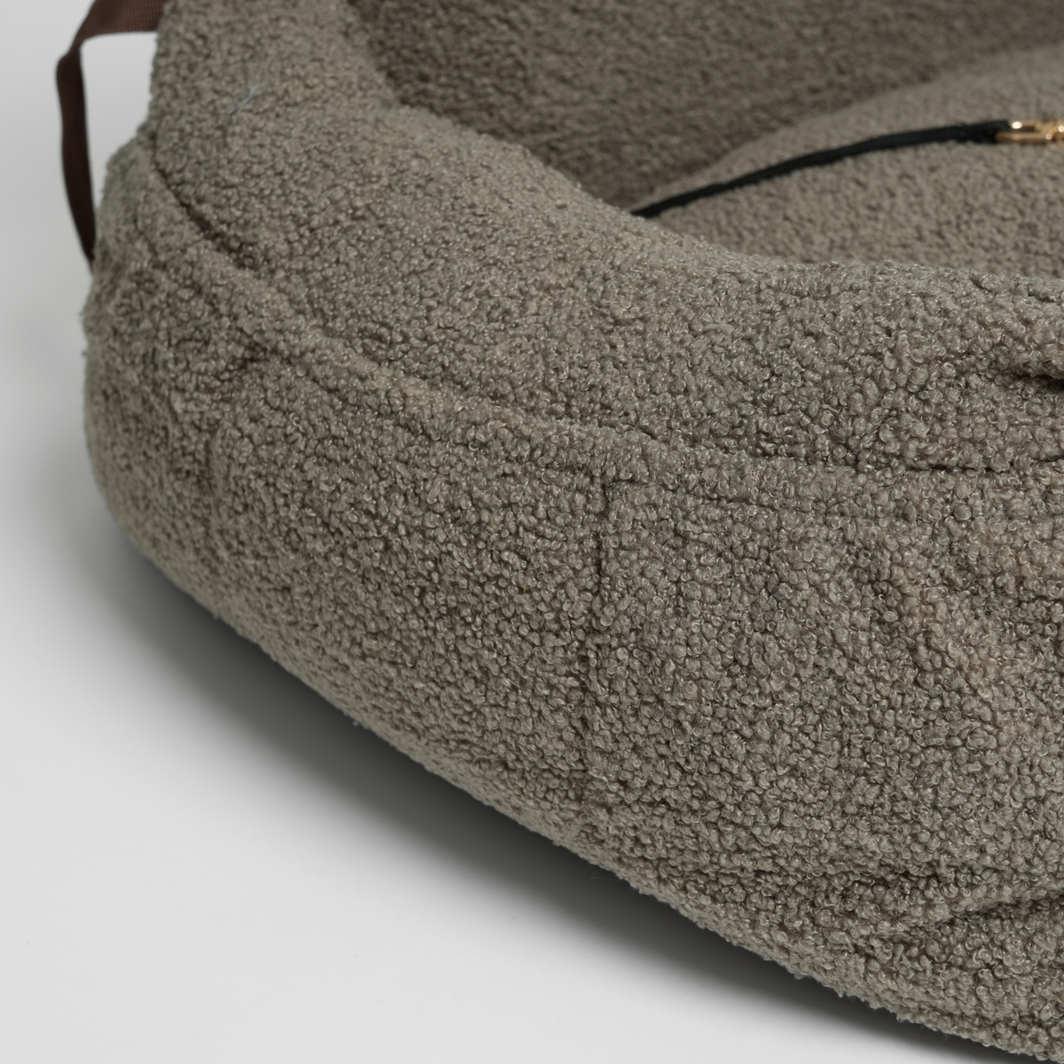 Close-up of the zip and shoulder strap on the moss green bouclé car seat