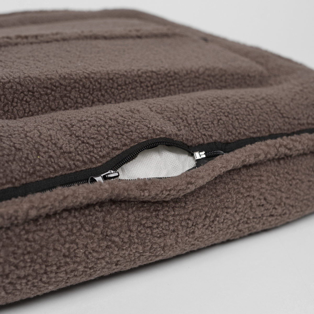 Close-up of the zip on the removable cover of the taupe teddy dog bed