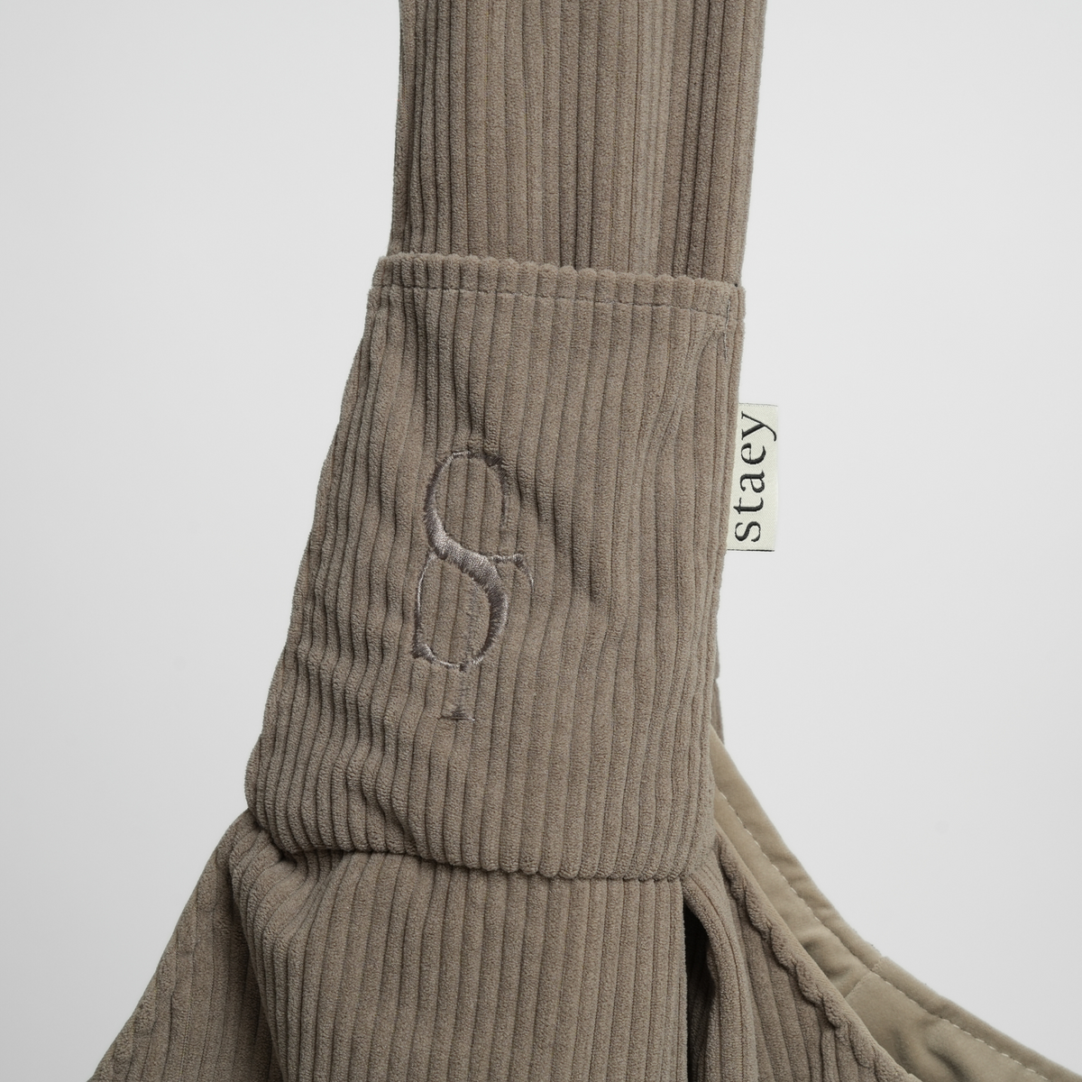Close-up of the embossed Staey monogram and label on the sling carrier