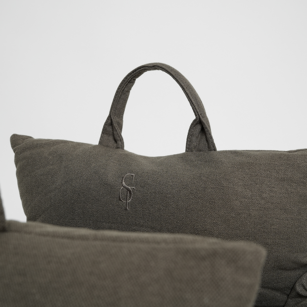 Close-up of the carry handle and embossed Staey monogram on a taupe car seat