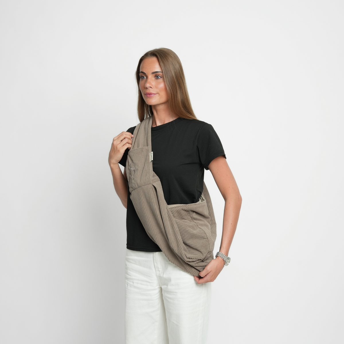 Woman wearing the taupe corduroy sling carrier over her shoulder