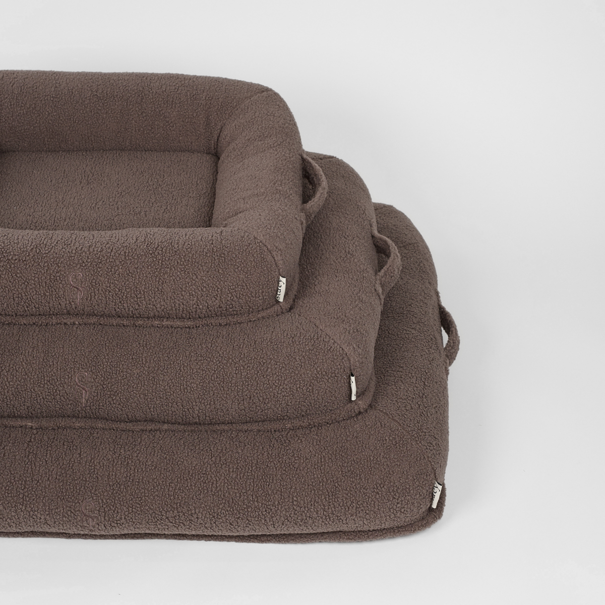 The taupe teddy dog bed shown in two sizes, stacked